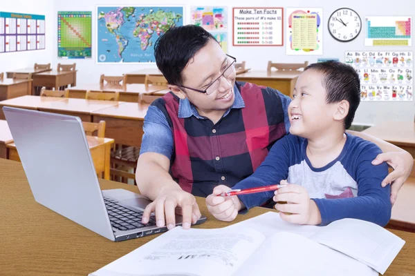 Teacher guiding male student in the classroom