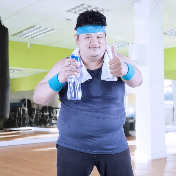 Obese man drinks water at gym 1