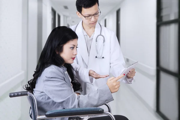 Disabled patient and doctor looking at tablet