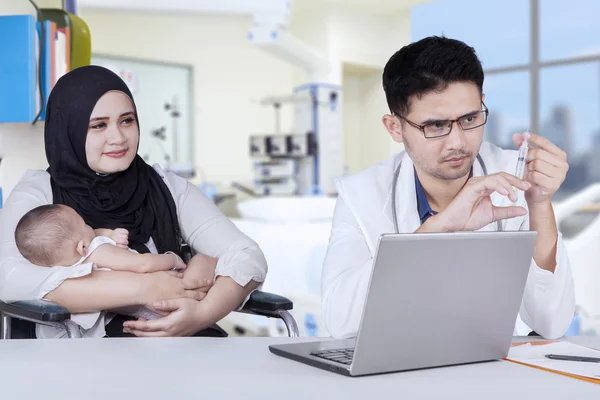 Physician holds syringe to give vaccine on the baby