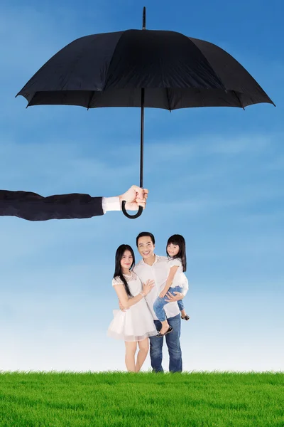 Family standing under umbrella at field