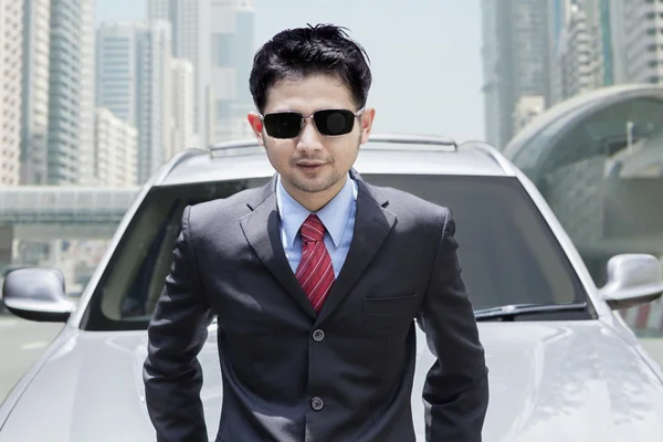Man wearing formalwear in front of new car