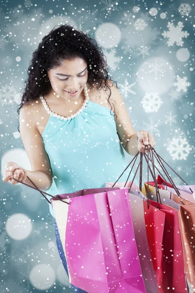 Woman opens shopping bags with winter background