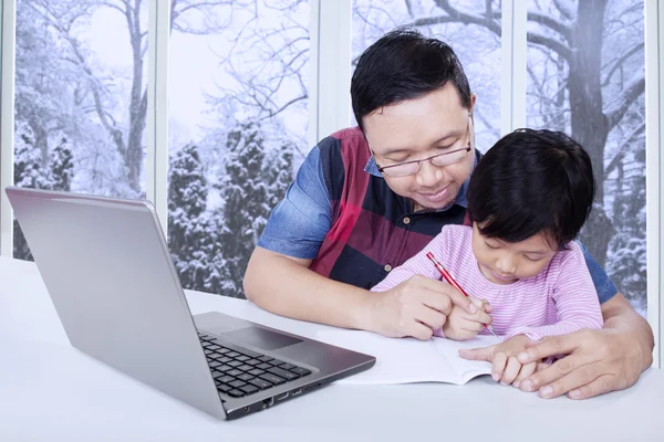 Dad helps his daughter doing school assignment