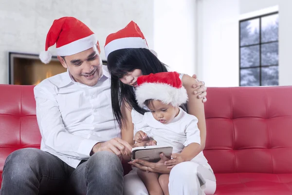 Family with santa hat using tablet on sofa