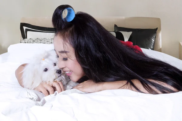 Pretty girl embrace her dog on bed