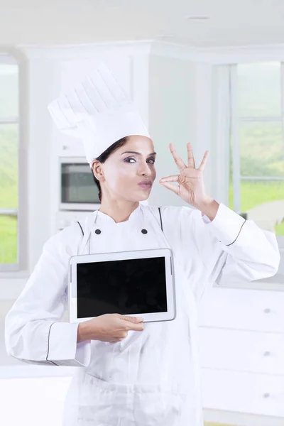 Attractive female chef with tablet in kitchen