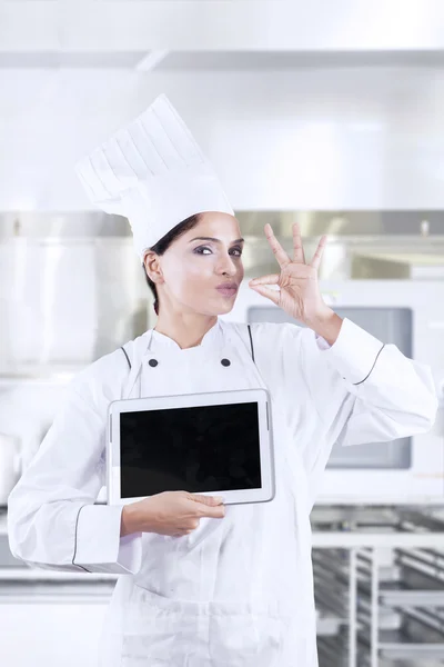 Young chef with deliciousness gesture and tablet