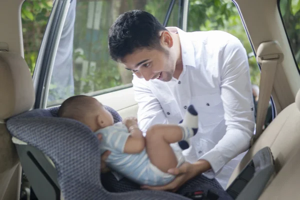 Father Putting his Baby on Car Seat