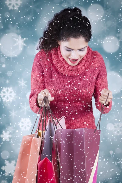 Woman opens shopping bags with winter background