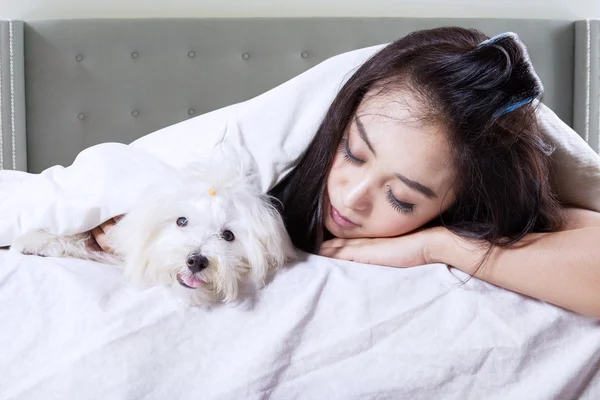 Lovely woman sleeping with puppy on bed
