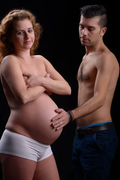 Pregnant woman and husband toughing her belly