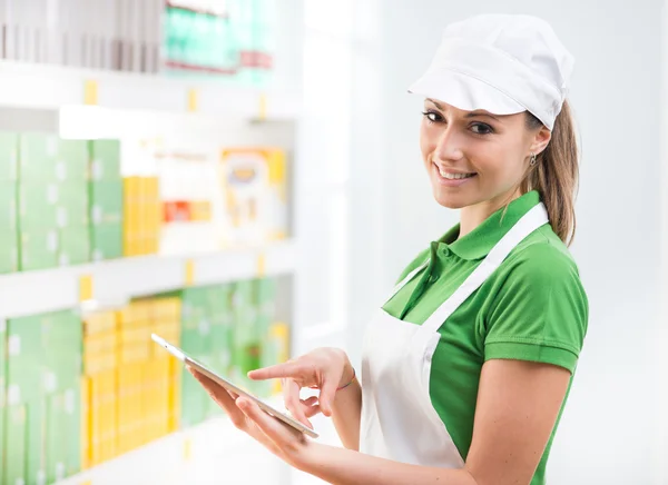 Female sales clerk with tablet at supermarket