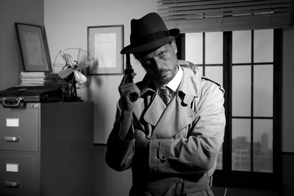 Film noir: detective holding a revolver and posing