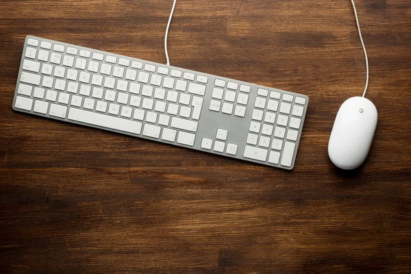 Keyboard and mouse on wooden background