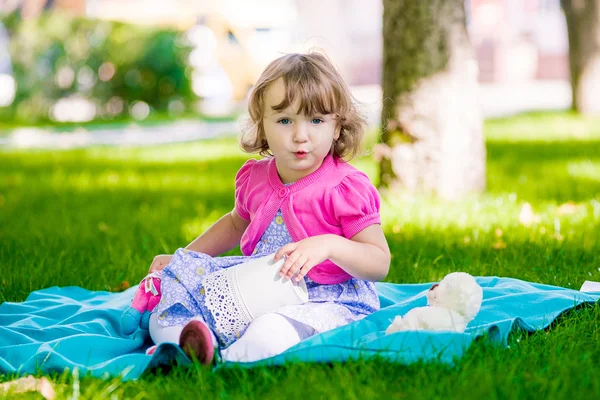 Little girl sitting in the park and reading a book