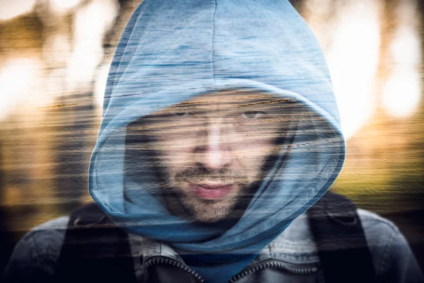 Close-up portrait of threatening gangster wearing a hood, concept of danger