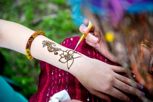 Picture of human hand being decorated with henna tattoo, mehendi