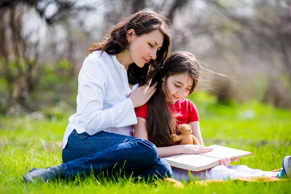 Happy Mom and daughter reading a book on nature