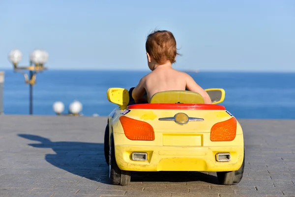 Little boy sitting in the car and looks at the sea