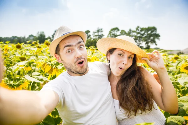 Young happy couple man and woman are in a field of sunflowers, make selfie pics