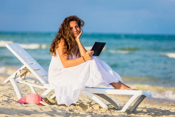 Young woman in hat with tablet pc at the beach