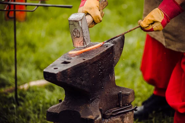 A smith forging a horse shoe on an anvil