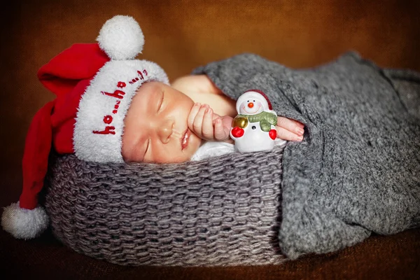 Newborn baby boy asleep wrapped in a blanket close-up in Santa hats