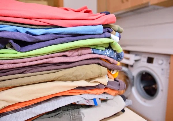 Close-up of pile of clean clothes against of washing machine