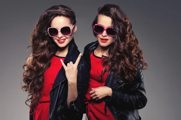 Sisters twins in hipster sun glasses laughing. Two fashion model