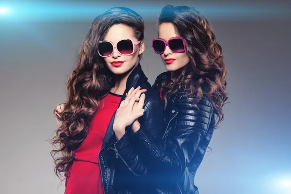 Sisters twins in hipster sun glasses laughing Two fashion models