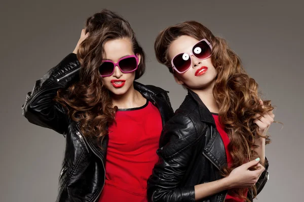 Sisters twins in hipster sun glasses laughing Two fashion models