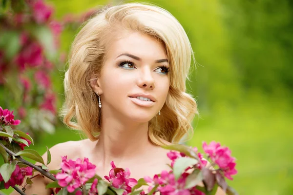 Young spring fashion woman. Trendy girl in the flowering trees in the spring summer garden. Springtime or summertime. Lady in spring landscape background. Allergic to pollen of flowers. Spring allergy