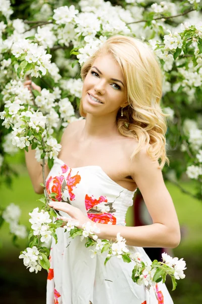 Young spring fashion woman. Trendy girl in the flowering trees i