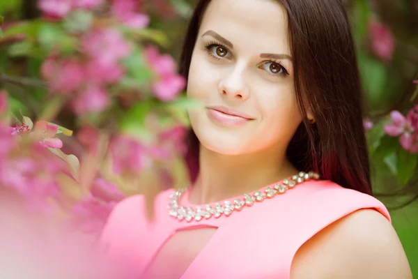 年轻的春季时尚女人。在春天夏天花园里的开花