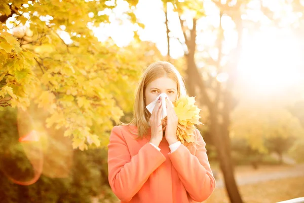 Girl with cold rhinitis on autumn background. Fall flu season. I