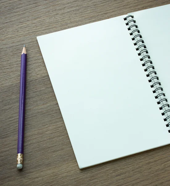 Blank spiral notebook and pencil on dark wood background