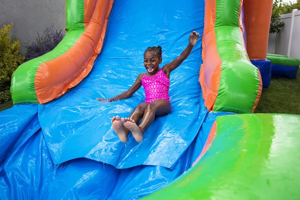 Happy little girl sliding down an inflatable bounce house.