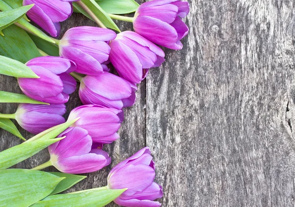 Bouquet of violet tulips on the oak brown table