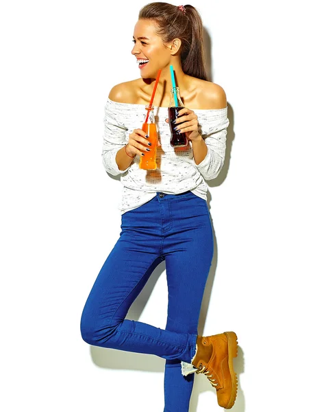 Portrait of beautiful crazy smiling brunette woman girl in casual blue hipster summer clothes with no makeup isolated on white drinking soda from two bottles with straw