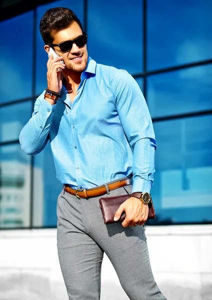 Fashion portrait of young sexy businessman handsome model man in casual cloth suit in sunglasses in the street speaking on his phone