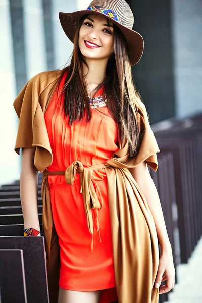 Funny stylish sexy smiling beautiful young hippy woman model in summer bright hipster clothes dress in the street in hat
