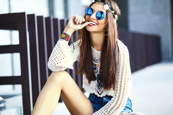 Funny stylish sexy smiling beautiful young hippy woman model in summer white fresh hipster clothes sitting in the street
