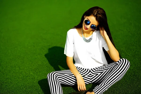 Funny crazy glamor stylish sexy smiling beautiful  young woman model in hipster clothes sitting in the grass in the park