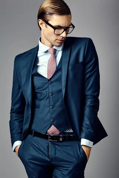 Young  elegant handsome  businessman male model in a suit and fashionable glasses, posing in studio