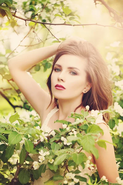 Beautiful Young Woman with Spring Flowers. Long Healthy Hair and Fashion Makeup. Beauty Girl with Flowers.