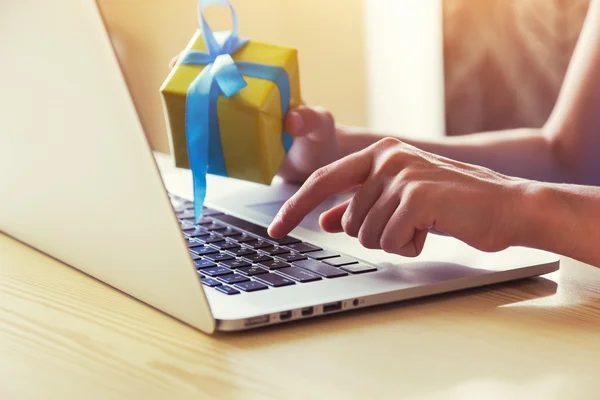 Hands with gift box and laptop