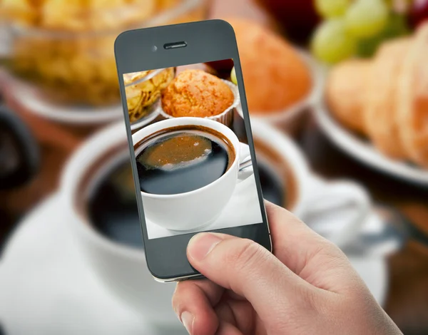Hand with smartphone taking food photo of fresh healthy breakfas