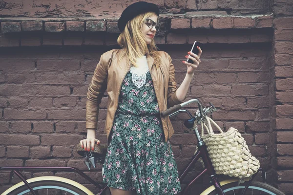 City lifestyle stylish hipster girl with bike using a phone text