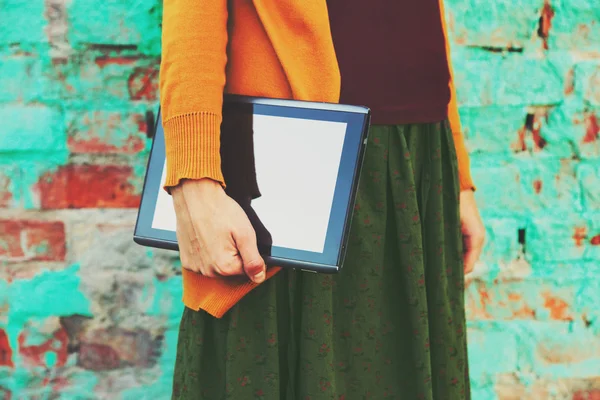 Hands holding digital tablet pc on colorful brick wall